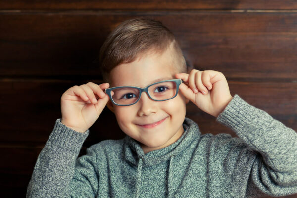 Child with glasses smiling on wooden background